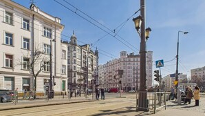 A street scene with tram tracks, buildings, and pedestrians. - Cozy Studio in the Center | Balcony and Proximity to Bathrooms (Warszawa)