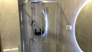 A modern bathroom with a glass-enclosed shower, a white toilet, and a sink with a wooden soap holder. - Quiet single room (Madrid)