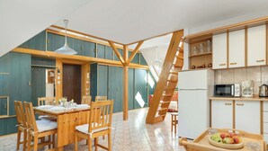 Una cocina moderna con armarios de madera, un comedor con mesa y sillas de madera, y una escalera que conduce a un nivel superior.