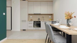 Una cucina moderna con mobili bianchi, forno integrato e zona pranzo con tavolo apparecchiato per due.