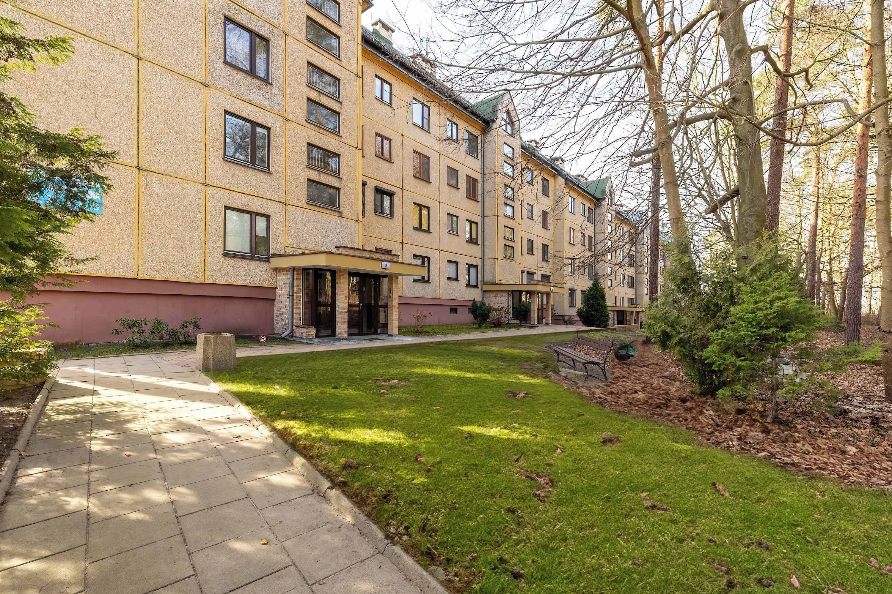 A multi-story residential building with a paved walkway and a grassy area.