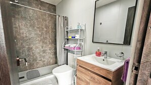 A modern bathroom with a shower, toilet, vanity with a mirror, and storage shelves. - H1 - 14th Floor Modern Studio with Stunning City Views, Wi-Fi & Washer/Dryer (La Paz)