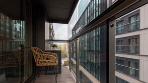 A balcony with wicker chairs, a small table, and a view of a cityscape.
