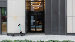 A modern building entrance with a teal electric scooter parked outside.