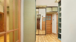 Un pasillo con suelo de madera, puertas correderas y una estantería.