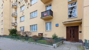 A multi-story residential building with balconies, a gated entrance, and a number sign indicating the building's address. - Spacious Apartment | 2 Bedrooms | Workspace (Warszawa)
