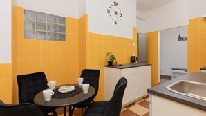 A compact kitchen with a clock, a dining table with chairs, and a small island with a sink. - Spacious Apartment | 2 Bedrooms | Workspace (Warszawa)