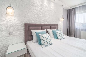 A modern bedroom with a textured white wall, a tufted headboard, and a large bed with patterned pillows.