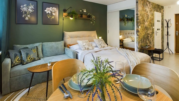 Ein modernes Schlafzimmer mit einem Bett, einer Couch, einem Esstisch mit Besteck und einem Kleiderständer.