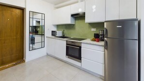 Eine moderne Küche mit weißen Schränken, einem Edelstahl-Kühlschrank, einer Mikrowelle und einer Kaffeemaschine.