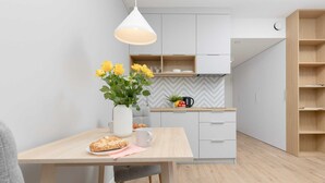 Eine moderne Küche mit Esstisch, einer Vase mit gelben Blumen und einer Kaffeemaschine.