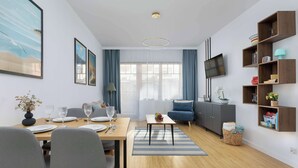 Ein modernes Wohnzimmer mit Essbereich, Holzböden, einem an der Wand montierten Fernseher und einem Bücherregal.