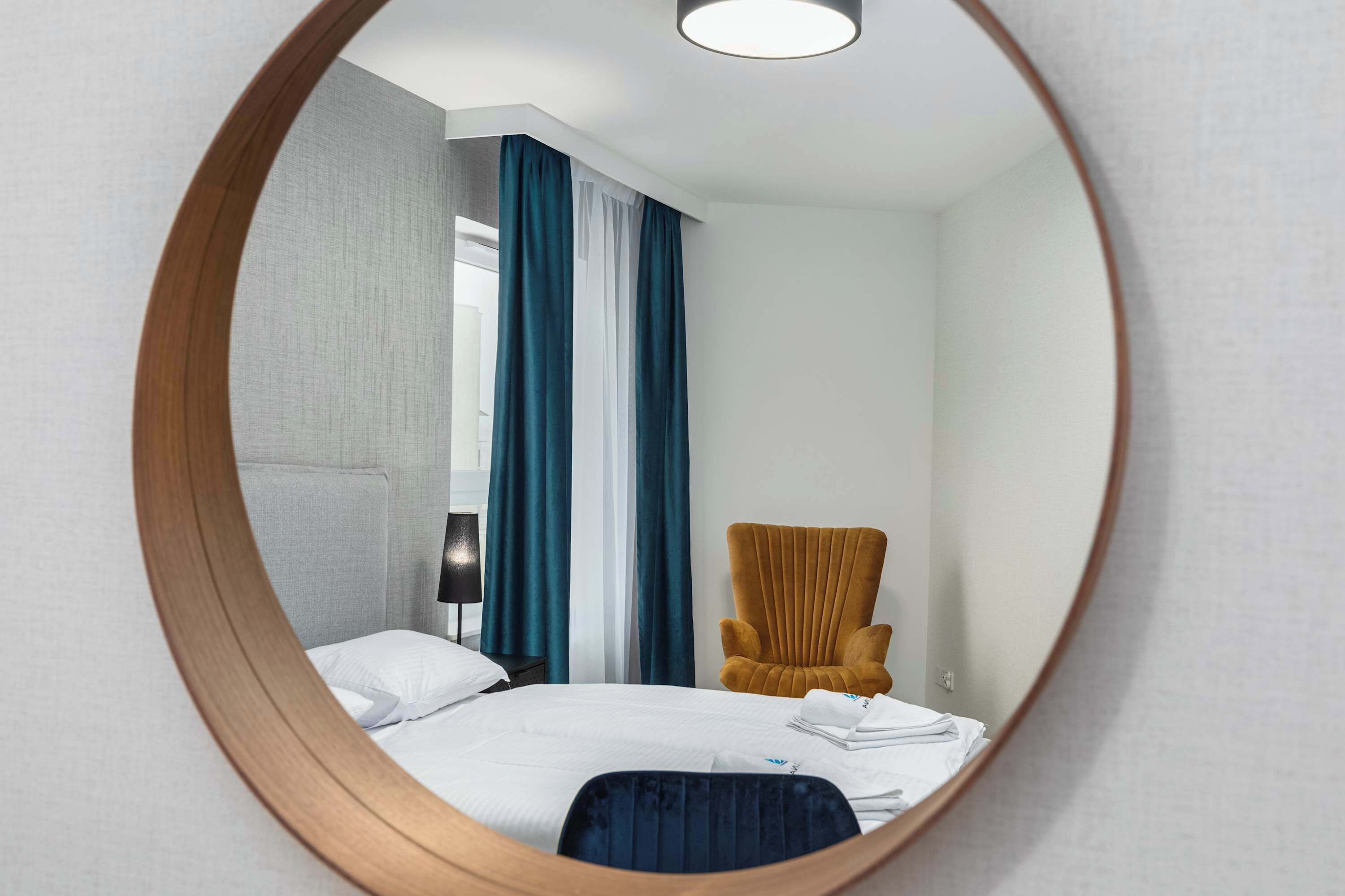 Una camera d'albergo con un letto, una sedia e uno specchio.