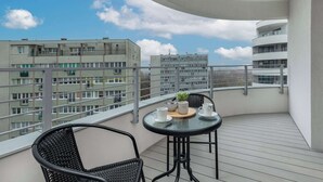 Un balcon avec une table ronde et deux chaises, donnant sur un paysage urbain composé de nombreux bâtiments.