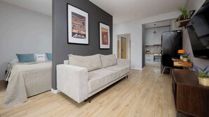 A modern living room with a sofa, a bed, and a kitchen area.