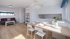 A modern living room with a sofa, coffee table, and dining area with chairs and a table set for four.