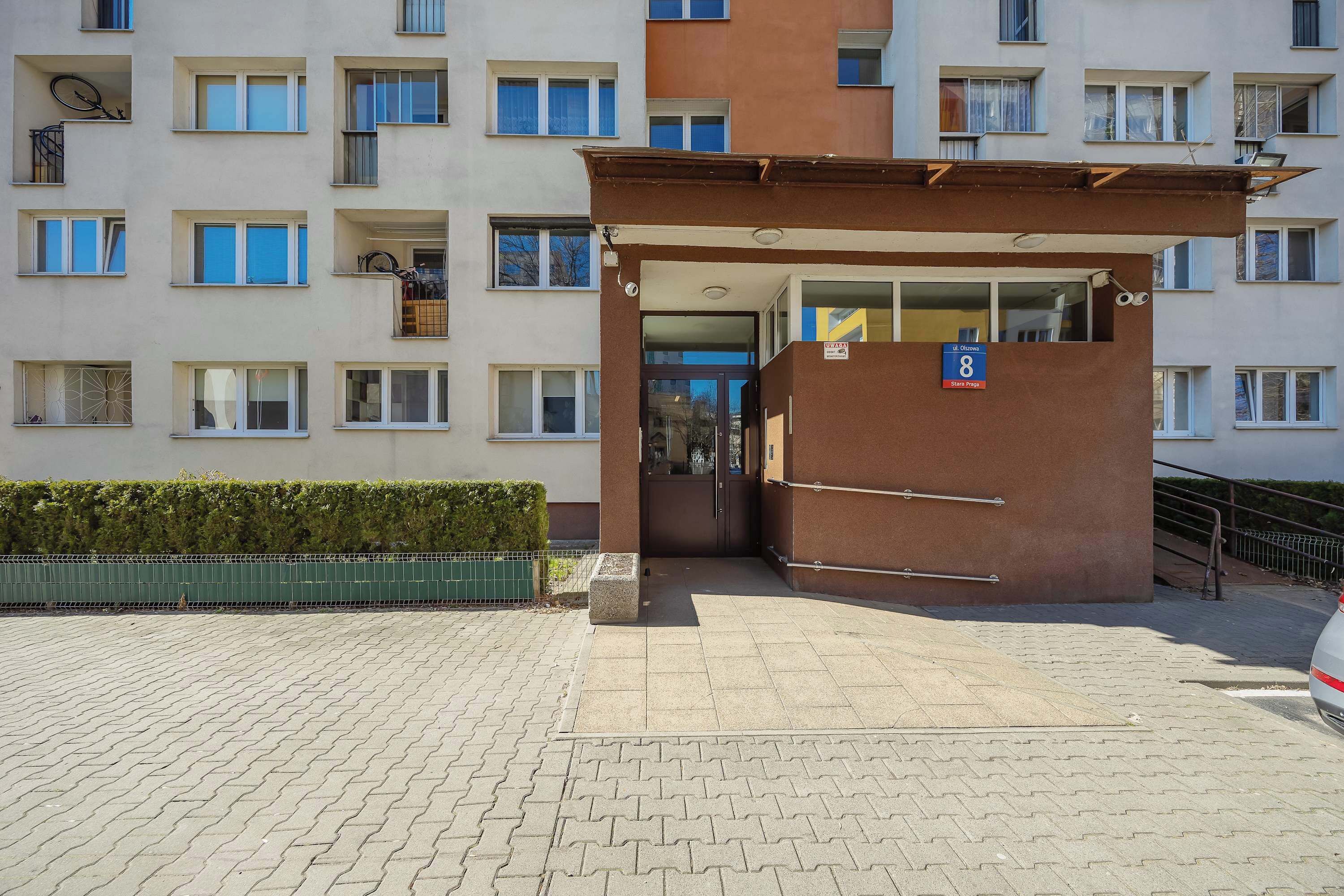 A multi-story building with a central entrance, a sign indicating room number 8, and a wheelchair-accessible ramp.