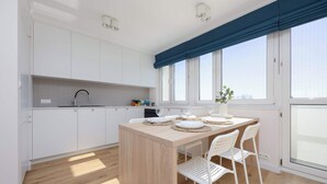 A modern kitchen with white cabinets, a wooden island, and a dining area with white chairs.