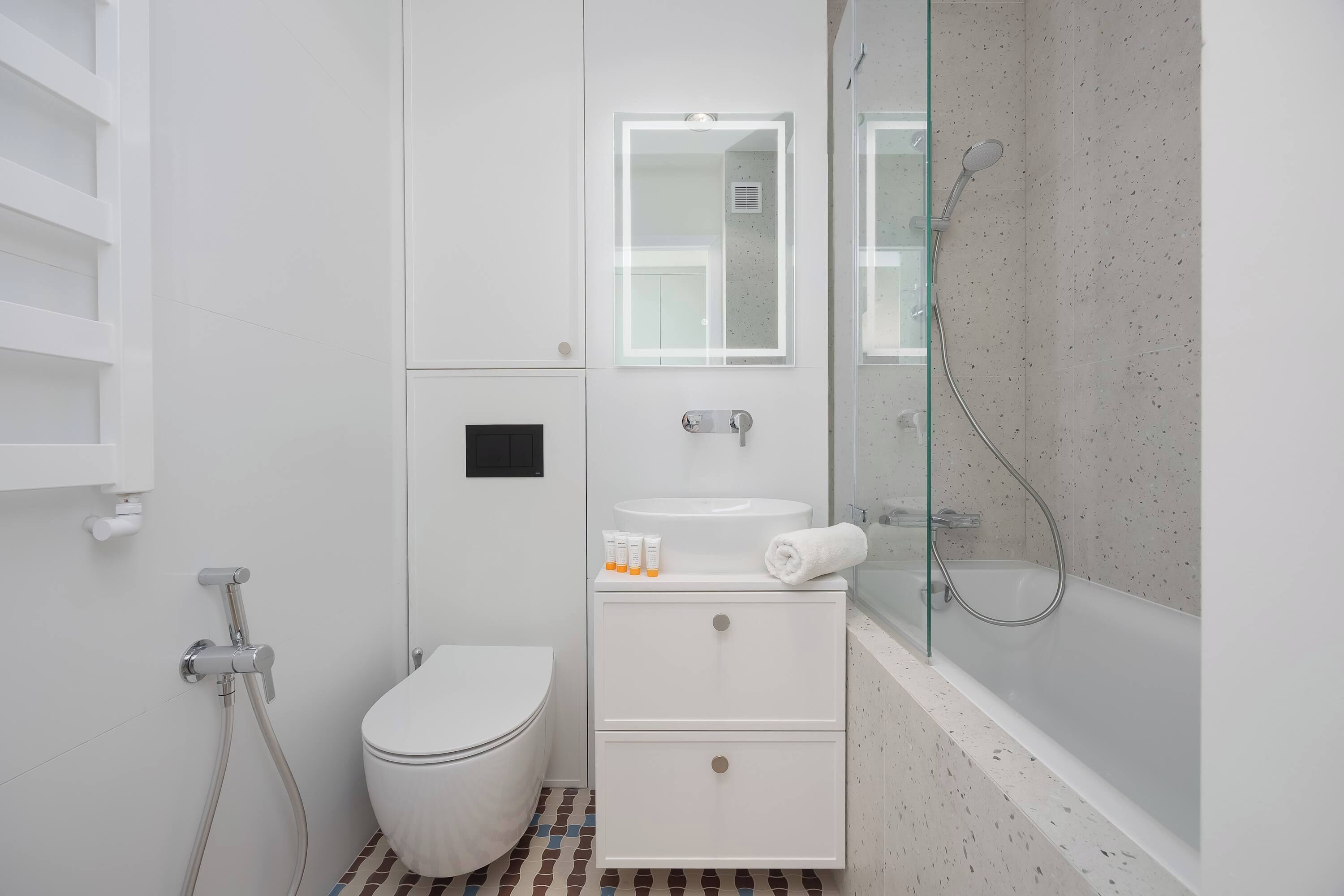 A modern bathroom with a toilet, a sink with a mirror, and a glass-enclosed shower area.