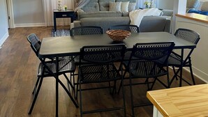 Un coin repas avec une table et des chaises, un ventilateur de plafond et un canapé en arrière-plan.