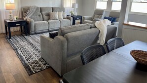 Un salon avec un canapé gris, une table à manger et un tapis à motifs.