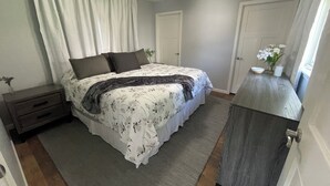 Une chambre à coucher comprenant un lit, une table de chevet, une commode et un ventilateur de plafond.
