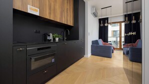 Eine moderne Küche mit schwarzen Schränken, Edelstahlgeräten und einer Wand in Holzoptik.