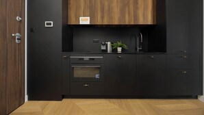 Eine moderne Küche mit dunklen Schränken, einem eingebauten Backofen und einer Kaffeemaschine.
