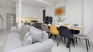 A modern living room with a grey sofa, dining table with chairs, and a kitchen in the background. - Spacious Apartment for 8 Persons | Air Conditioning (Warszawa)
