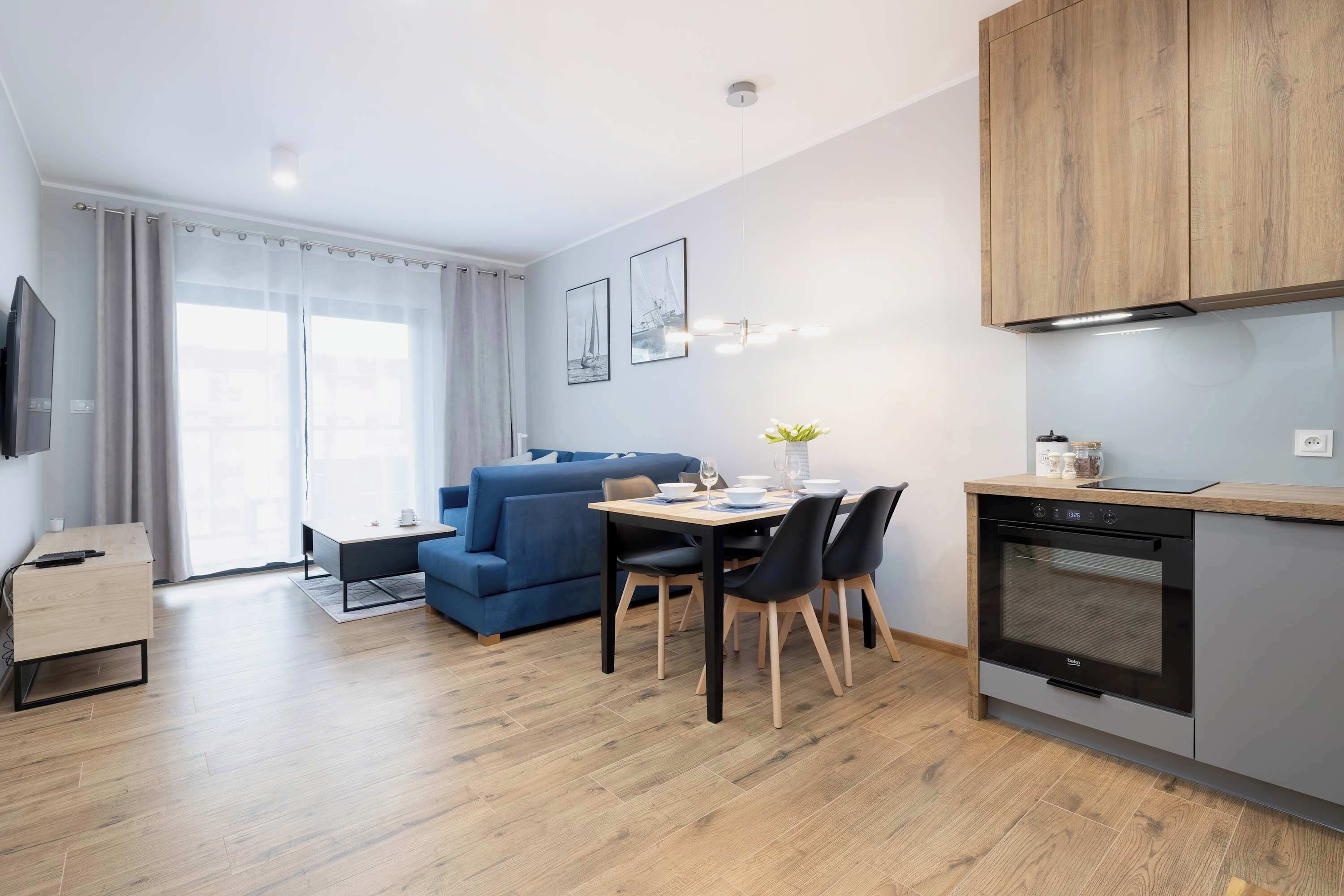 Una cocina moderna con armarios de madera, horno empotrado y comedor con mesa y sillas.