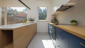 A modern kitchen with a wooden countertop, blue cabinets, and a hexagonal tile floor.