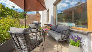 An outdoor patio with a sofa, chairs, and a large umbrella.