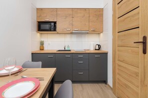 A compact kitchen with a microwave, wooden cabinets, a sink, and a dining area with a table and chairs.