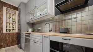 A modern kitchen with grey cabinets, a wooden countertop, and a built-in oven.
