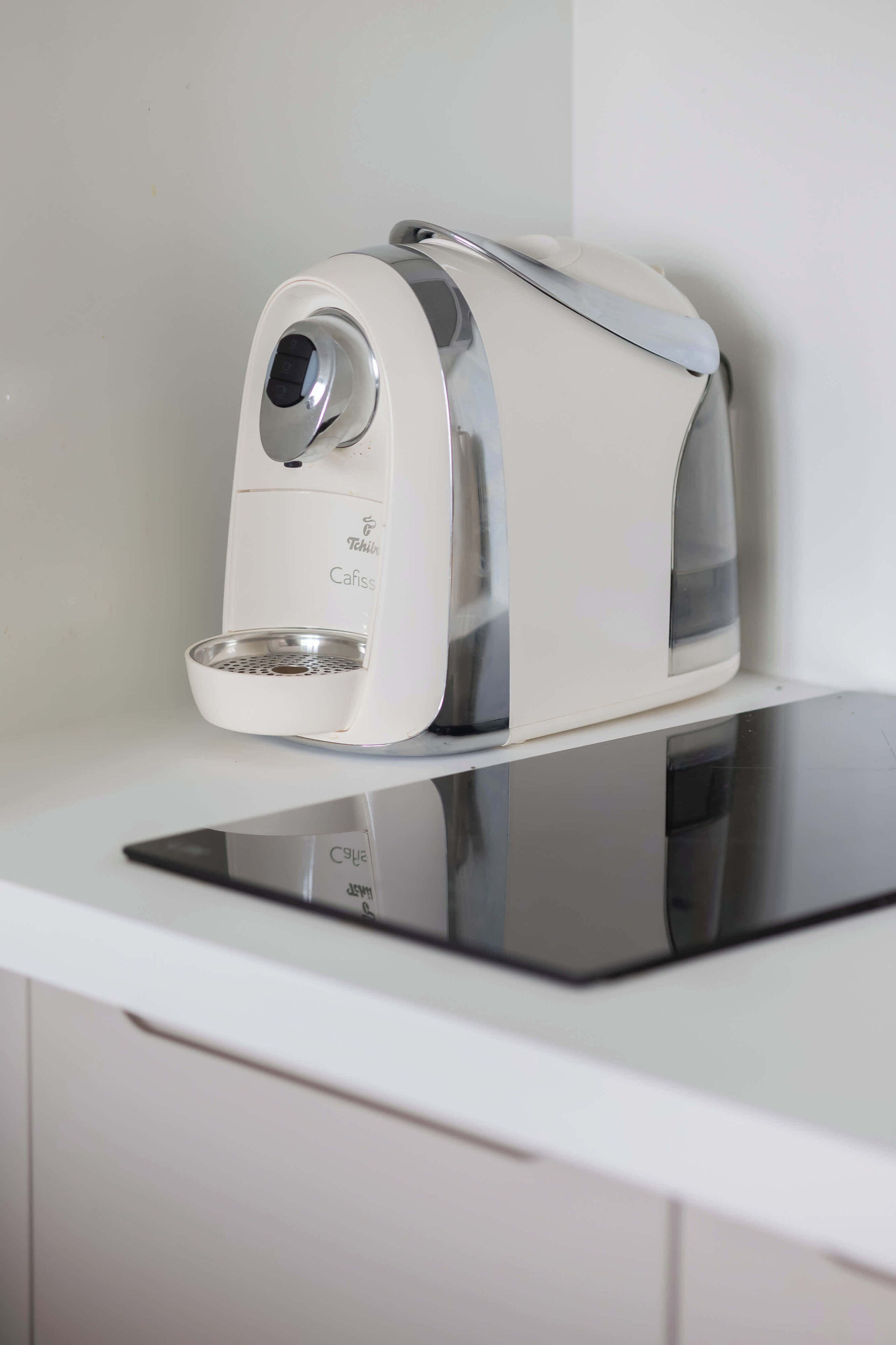 A white electric coffee maker on a white countertop.