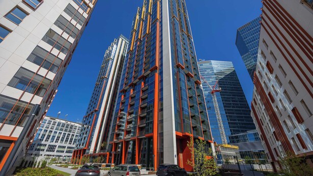 A modern high-rise building with multiple floors, large windows, and a prominent red and blue color scheme.