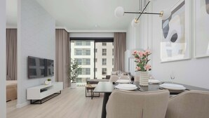 A modern living room with a flat-screen TV, a dining area with a table set for two, and a sofa.