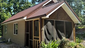 A single-story house with a brown roof, beige siding, and a small porch area.
