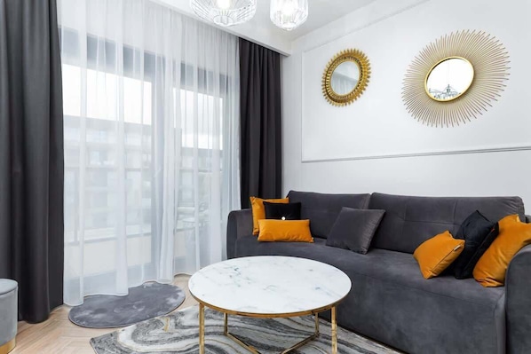 Un salon moderne avec un canapé gris, deux miroirs encadrés de doré et une table basse en marbre.