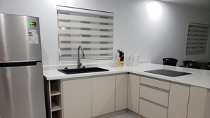 Een moderne keuken met een roestvrijstalen koelkast, een dubbele spoelbak en lichtkleurige kasten.