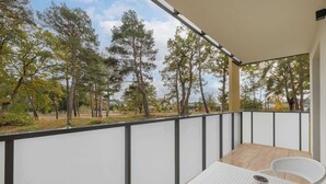 A balcony with a table, chairs, and a view of trees. - Cozy Apartment close to the beach | Parking in the garage (Dąbki)