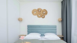 A neatly arranged bedroom with a bed, bedside tables, a wall-mounted decorative piece, and a window with curtains. - Cozy Apartment close to the beach | Parking in the garage (Dąbki)