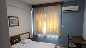 A hotel room with a bed, a desk, and an air conditioning unit. - Hotel Transcontinental (Ji Parana)