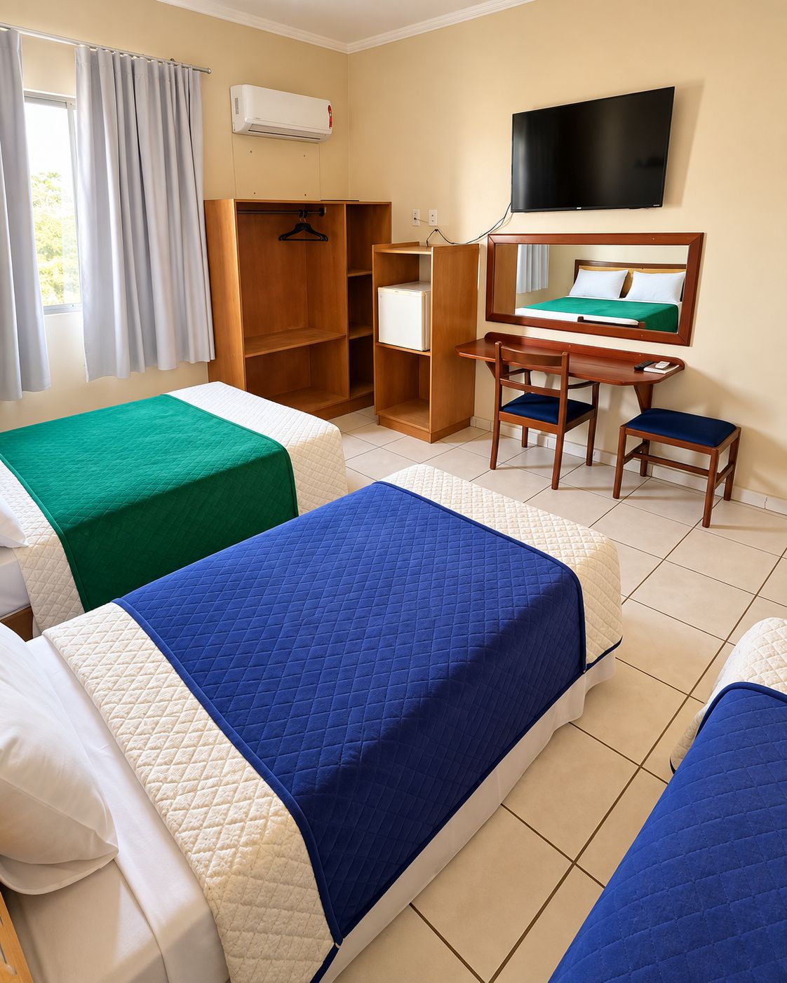 Habitación de hotel con dos camas, un escritorio, una silla, un televisor y un armario.