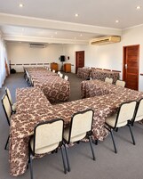 Una sala de conferencias con una larga mesa, sillas, un equipo de aire acondicionado, un orador y una puerta.