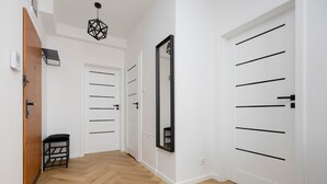A hallway with wooden flooring, white walls, and doors with black handles.