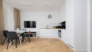 A modern kitchen with white cabinetry, a wooden countertop, and a built-in oven.