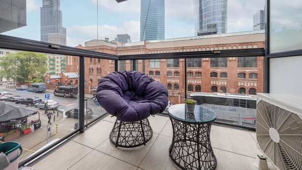 A modern balcony with a purple chair, a small table, and a fan. - Comfortable Apartment in the Center | Parking, AC, Balcony (Warszawa)