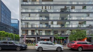 A multi-story building with a modern glass facade, a Starbucks, and a 'Zubkov Cafe' sign. - Comfortable Apartment in the Center | Parking, AC, Balcony (Warszawa)
