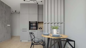 A modern kitchen with grey cabinets, a wooden dining table, and black chairs. - Comfortable Apartment in the Center | Parking, AC, Balcony (Warszawa)